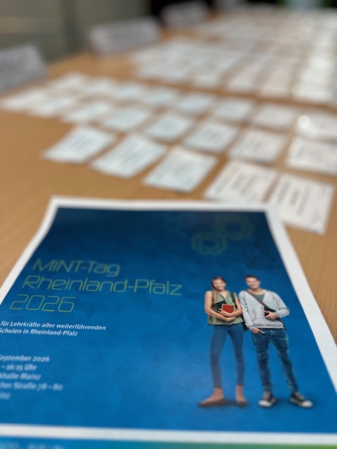 Programmheft MINT-Tag Rheinland-Pfalz 2026 auf einem Tisch mit Namensschildern