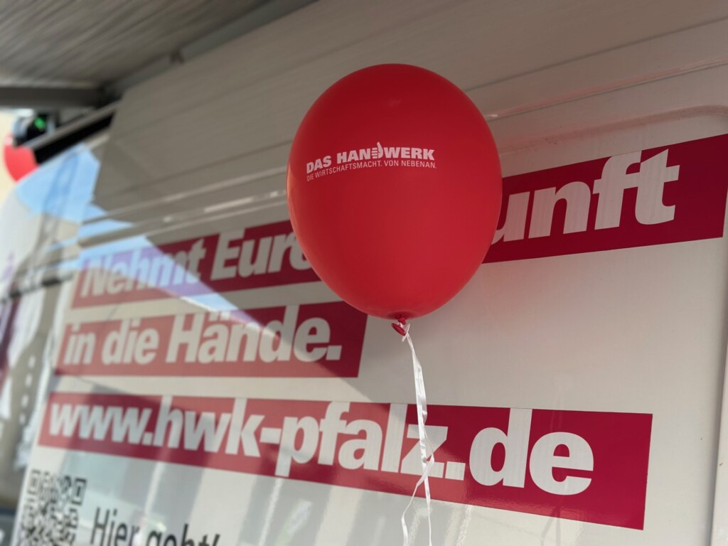 Roter Luftballon „Das Handwerk“ vor einem Banner der Handwerkskammer der Pfalz