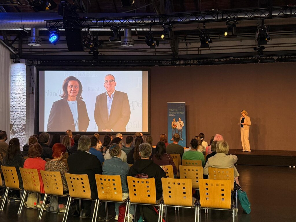 Lehrkräfte beim MINT-Tag Rheinland-Pfalz 2026 in der Alten Lokhalle Mainz, auf der Leinwand eine Videobotschaft
